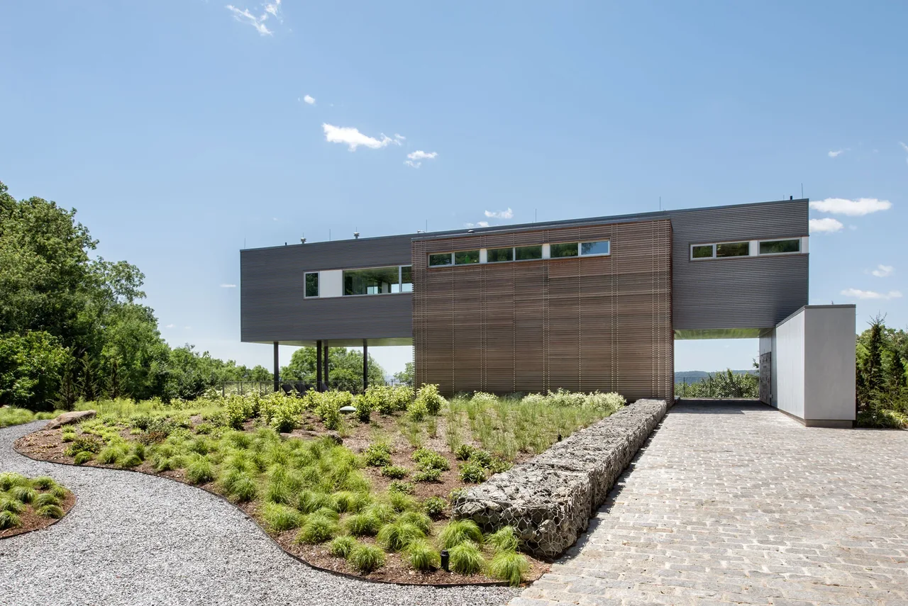 Hudson River House by Resolution 4 Architecture features a modern metal-clad cantilevered design with wood accents and horizontal windows.