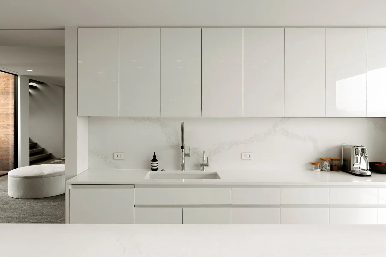 Kitchen in a residence featuring sleek white cabinets and a marble backsplash by Resolution 4 Architecture.