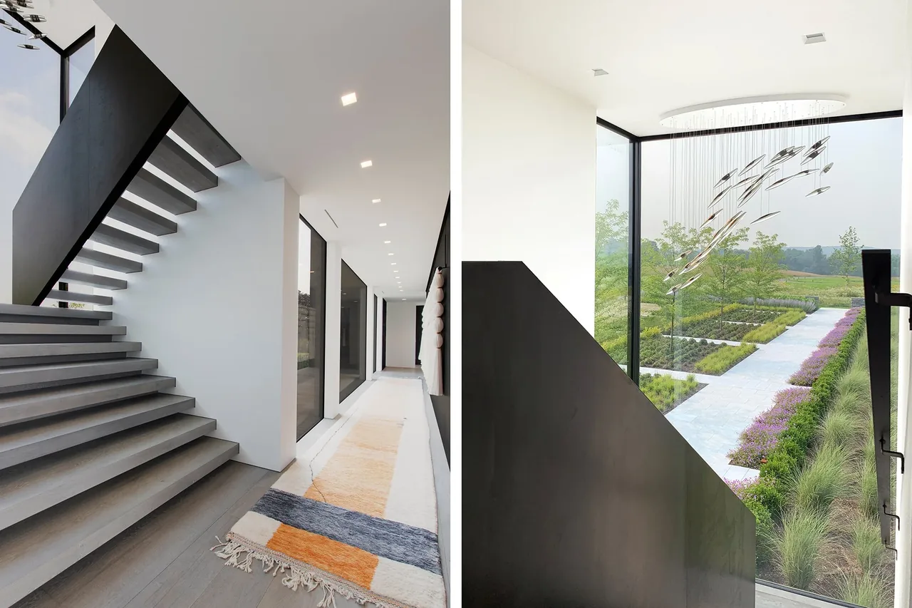 Hallway features floating stairs and expansive floor-to-ceiling windows overlooking landscaped gardens.
