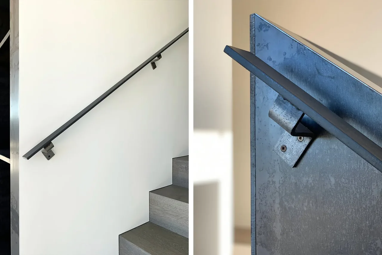 Modern staircase with gray wood steps and a sleek black metal handrail at the Millbrook Residence, Dutchess County, NY.