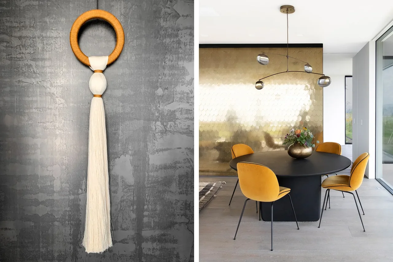 Dining space in Millbrook Residence features a black round table, orange chairs, a gold reflective accent wall, and modern pendant lighting.
