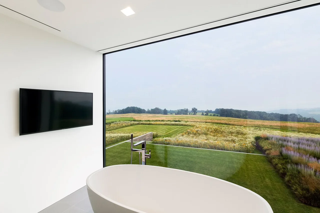 Bathroom features a freestanding tub with a large floor-to-ceiling window offering views of the surrounding landscape.