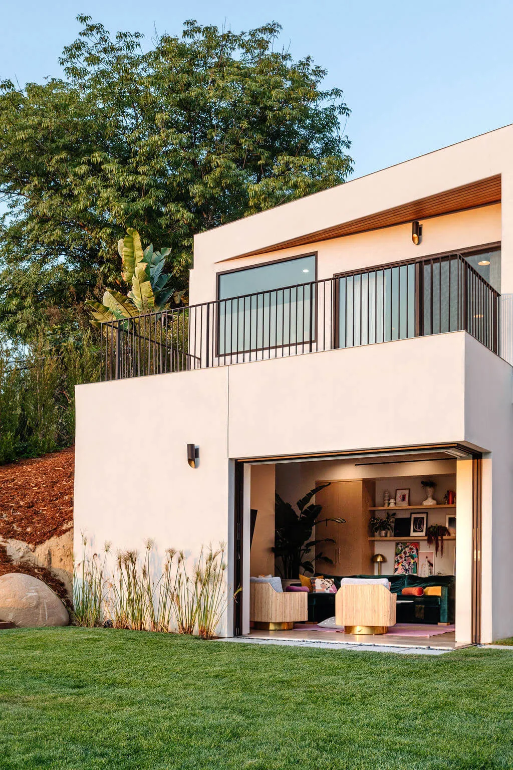 Hillside Home + Studio features a balcony with black metal railing and an open ground floor living area.