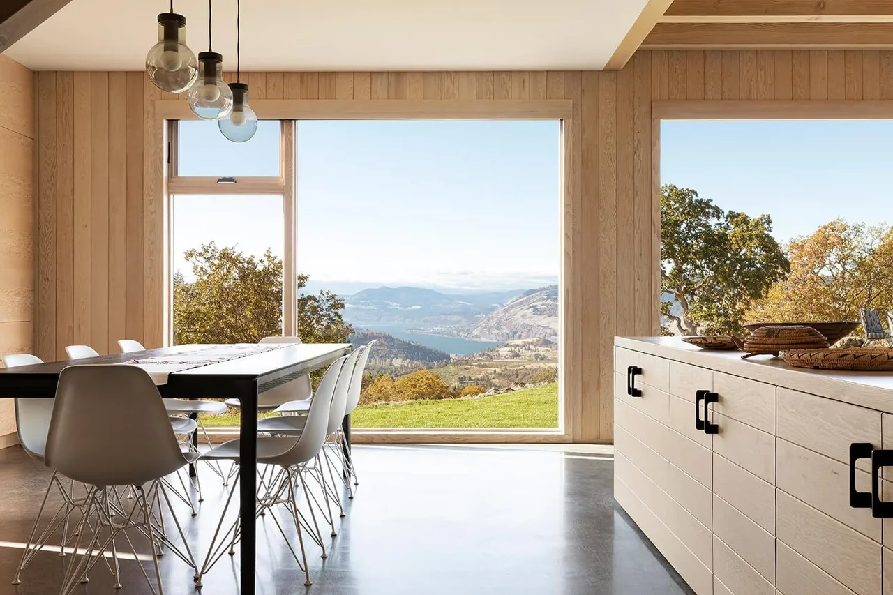 The Mosier House dining area features wood paneling and large windows framing scenic views of the hillside and river.