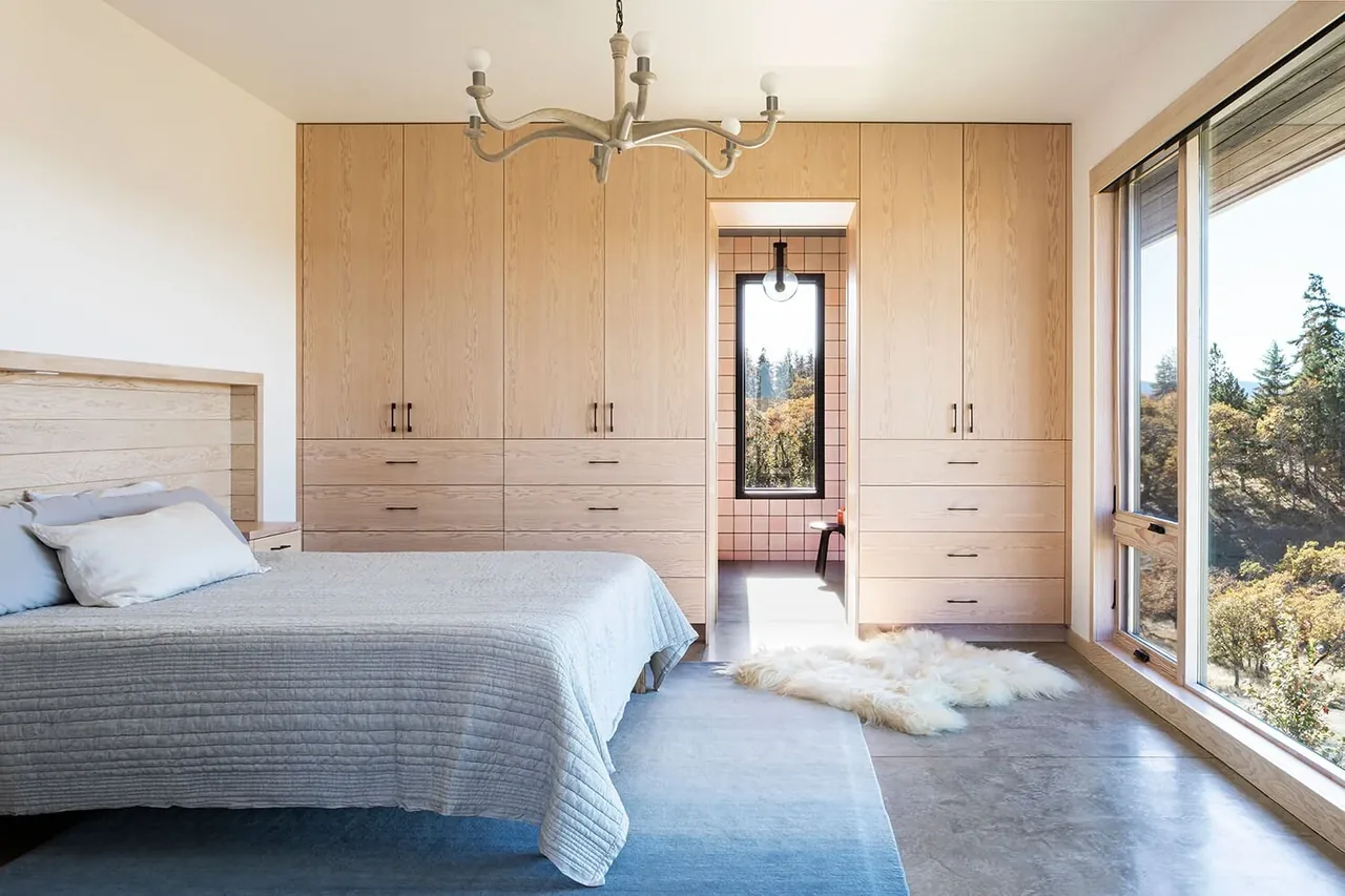 Bedroom features built-in wood cabinetry and a large picture window with landscape views.