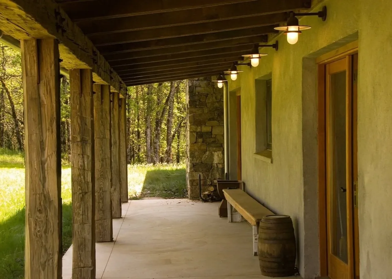 Outdoor porch area of Columbia Gorge House featuring wooden posts and wall-mounted lights under a wooden roof.