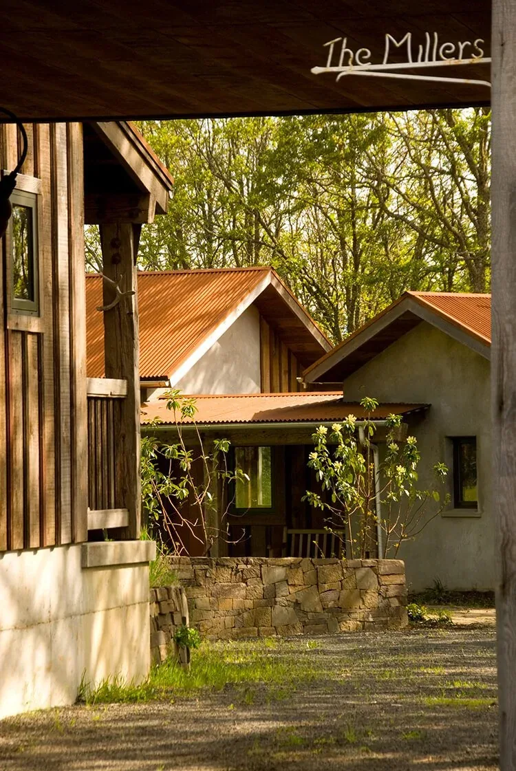 Columbia Gorge House exterior view with wood siding, rust-colored metal gable roofs, and stone retaining wall.