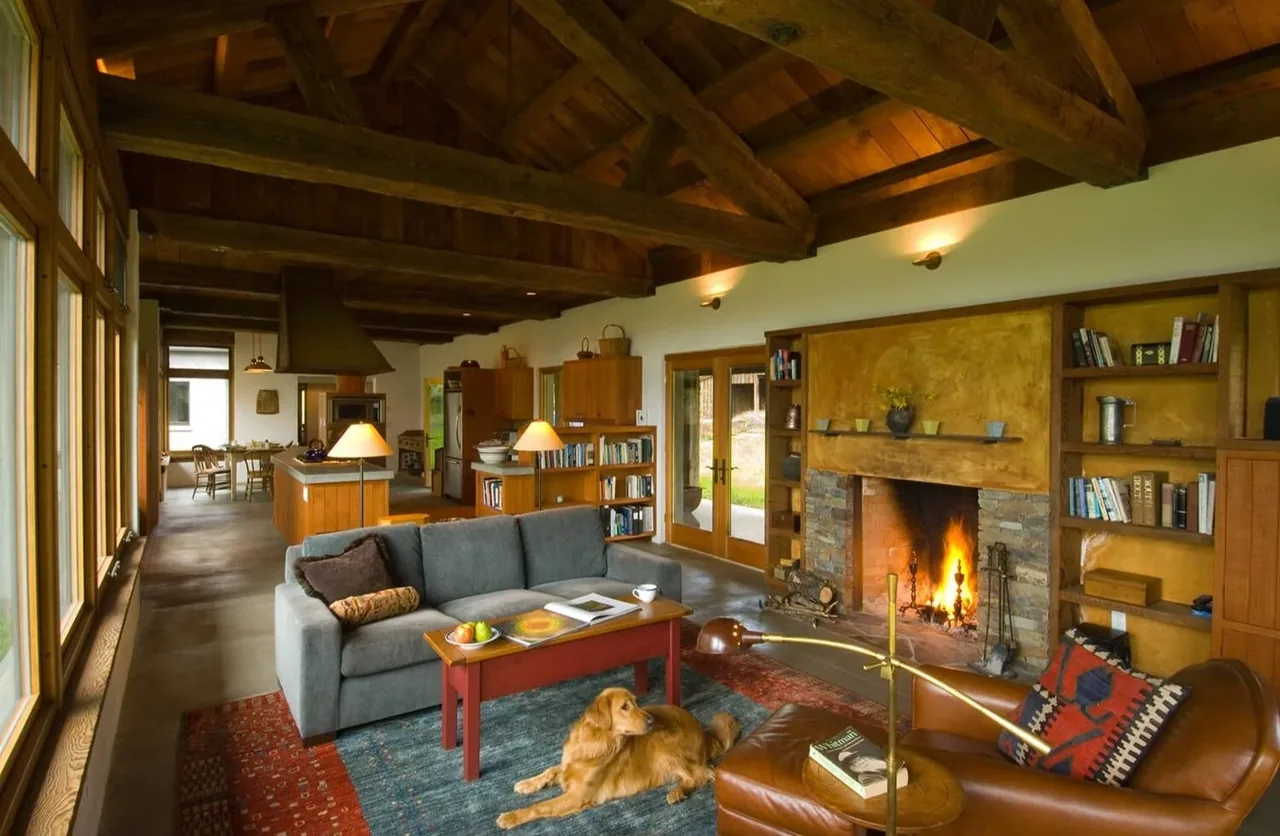 Living room with vaulted ceiling, stone fireplace, and built-in bookshelves at Columbia Gorge House by Richard Brown Architects.