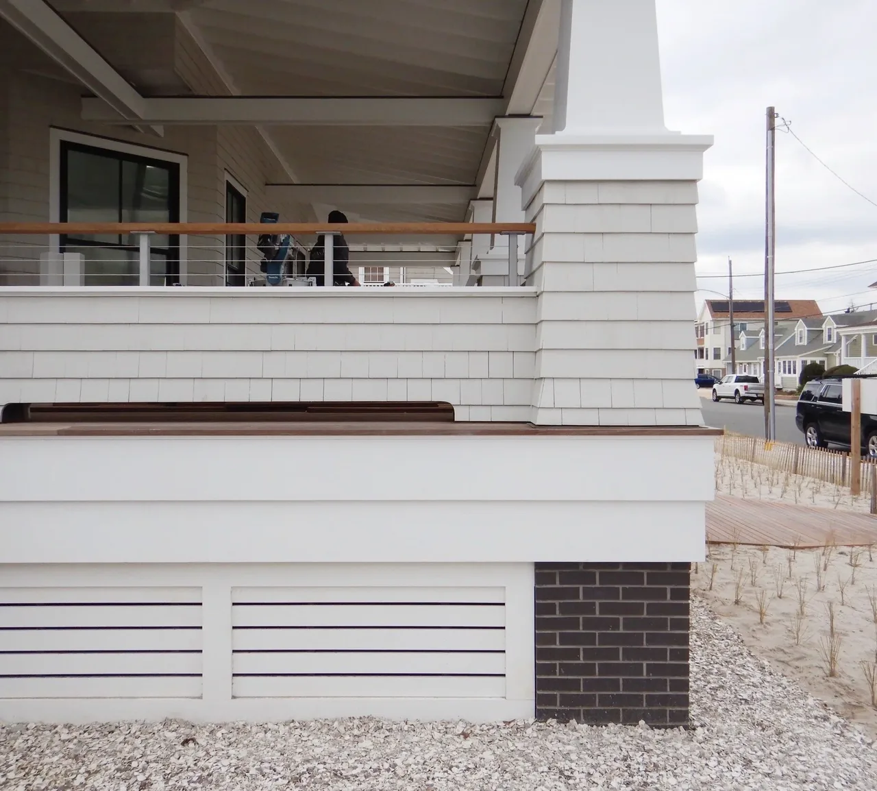 The Porch Talk House features a wrap-around porch with tapered columns, white shingle siding, and cable railing.