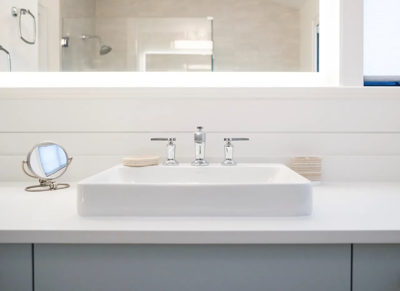 White rectangular sink with chrome faucet and accessories on a clean bathroom countertop.