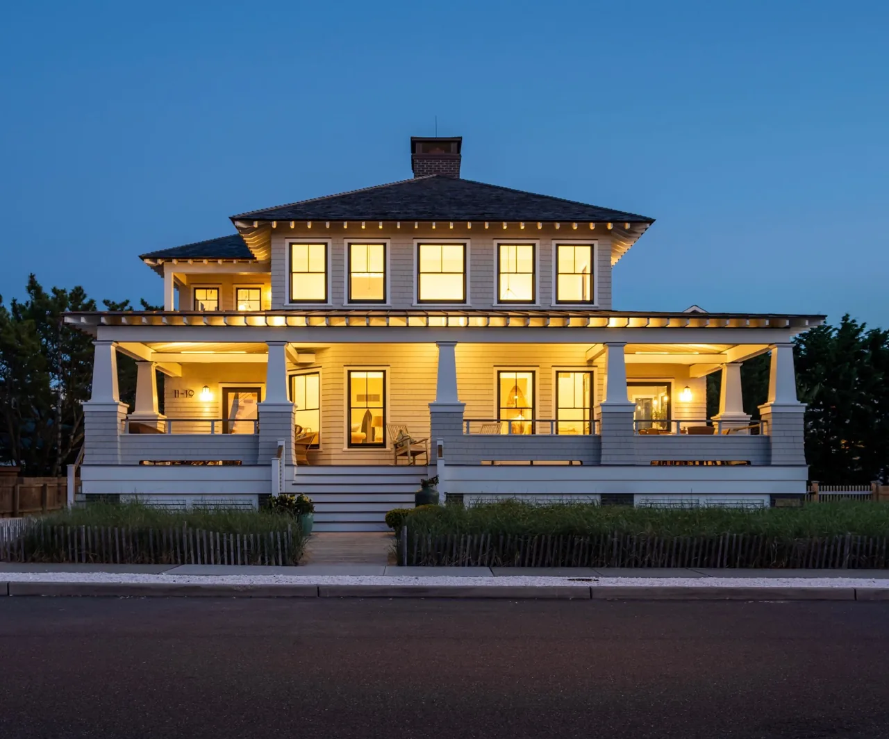 Porch Talk House at dusk showing its symmetrical windows, wide front stairs, and hip roof design.