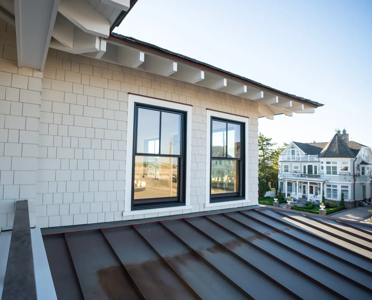 Exterior detail of a shingle house with black window frames and standing seam metal roof at Porch Talk House, Seaside Park.