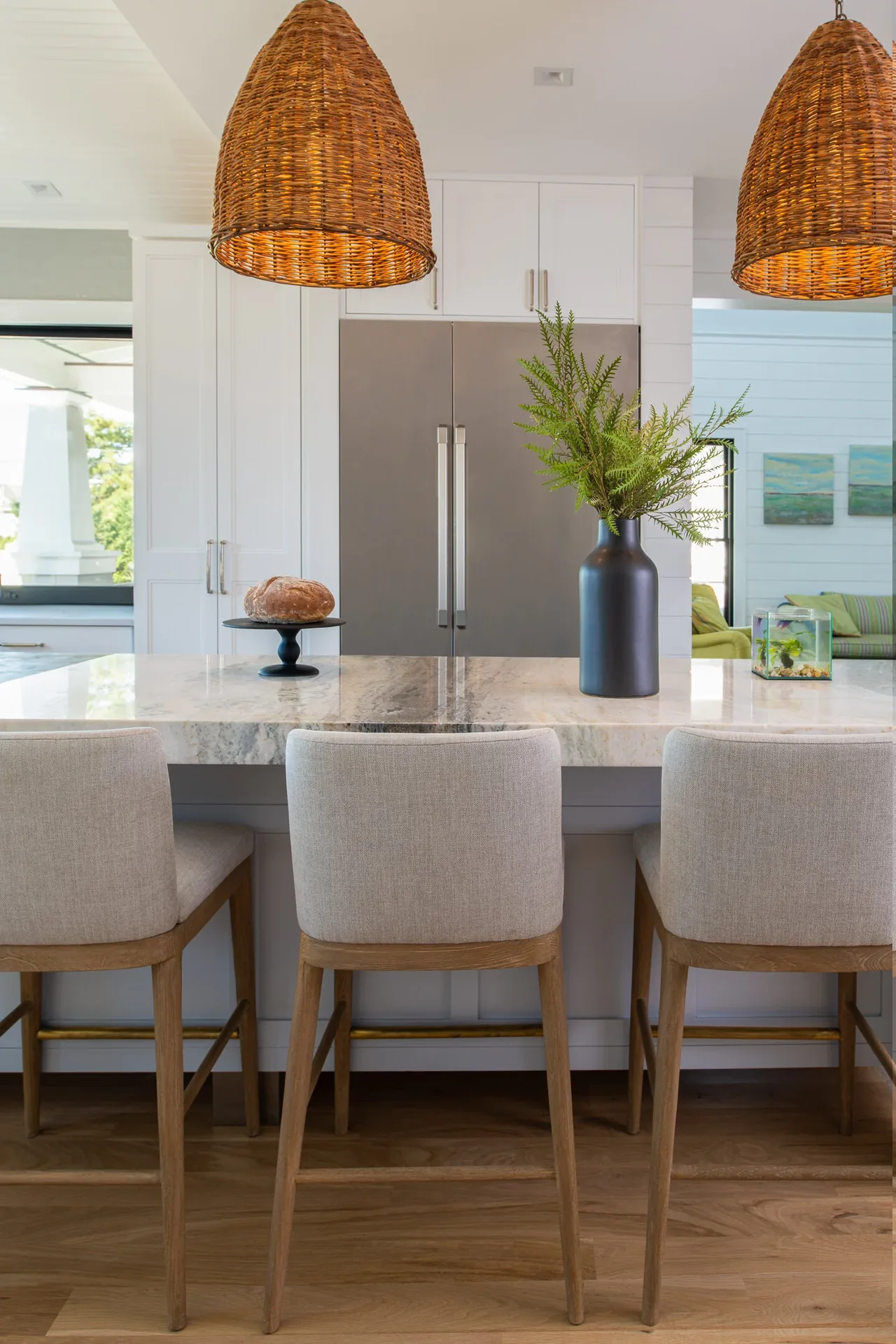 Kitchen with large granite island, built-in stainless steel refrigerator, and woven pendant lights in Porch Talk House.