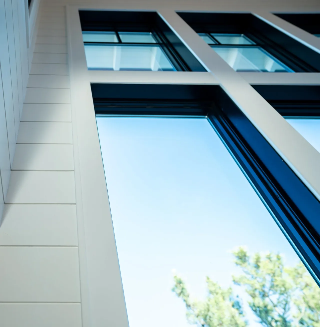 Exterior detail of white wood siding and large black-framed windows with rectangular panes.