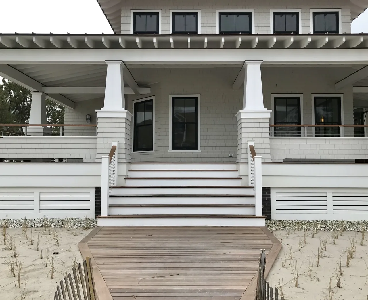 Porch entry of Porch Talk House showing white shingle siding, black framed windows, and tapered porch columns