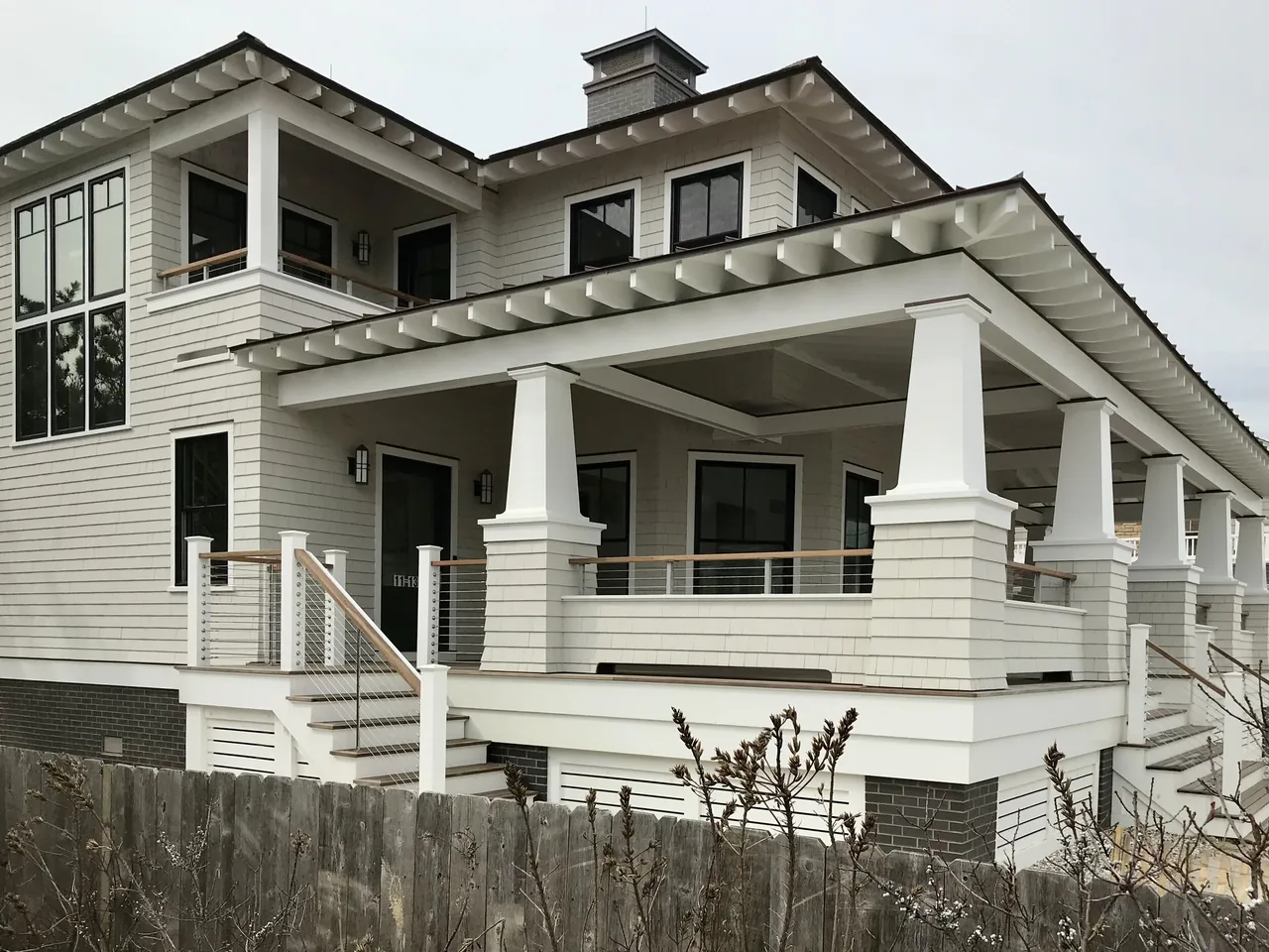 Porch Talk House in Seaside Park by Richard Bubnowski Design features white shingle siding and a spacious covered porch with cable railings.
