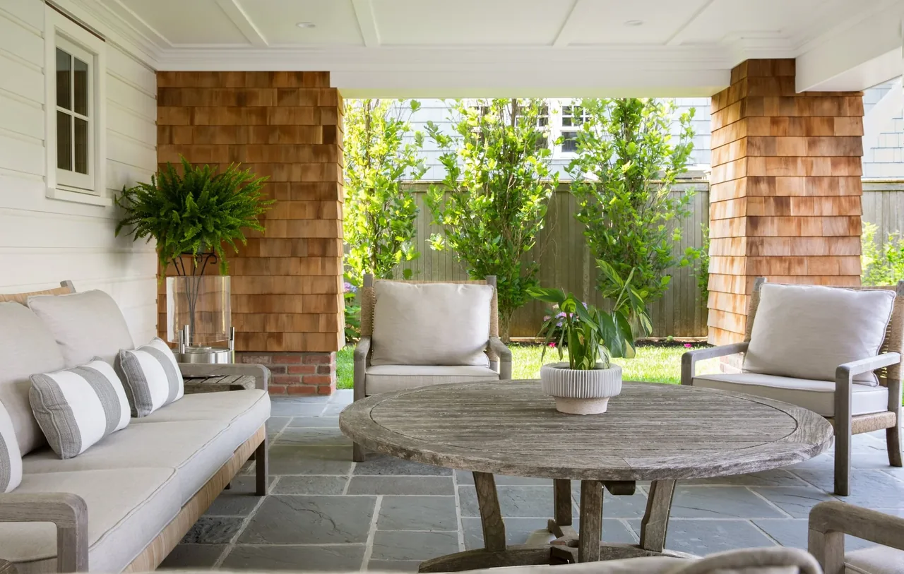 The Hagerstrom residence features a covered patio with wood-shingle columns and comfortable outdoor seating.