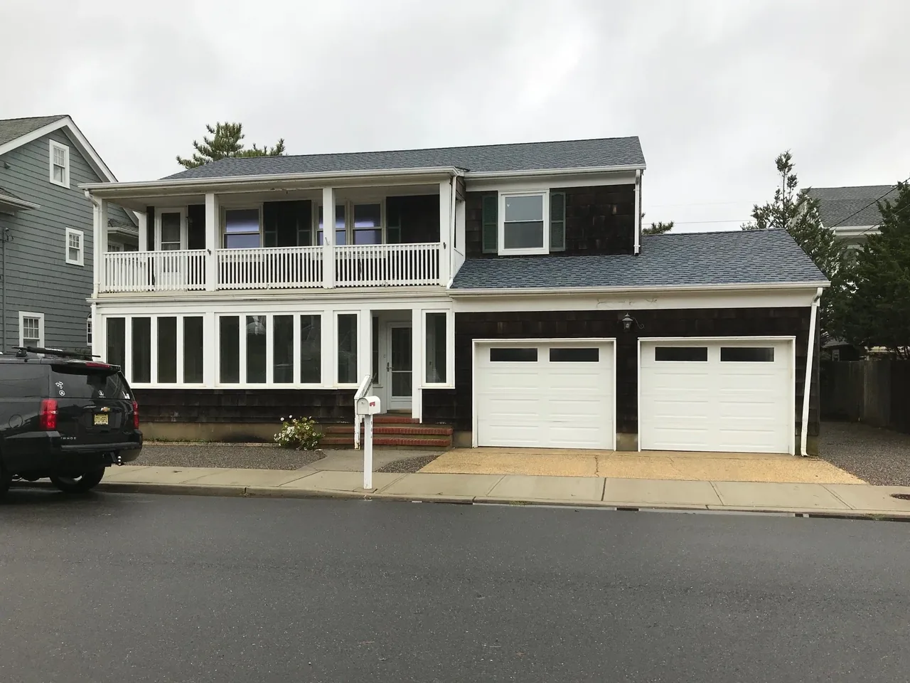 Hagerstrom residence features a raised porch with white railings, dark wood siding, and a double garage with white doors.