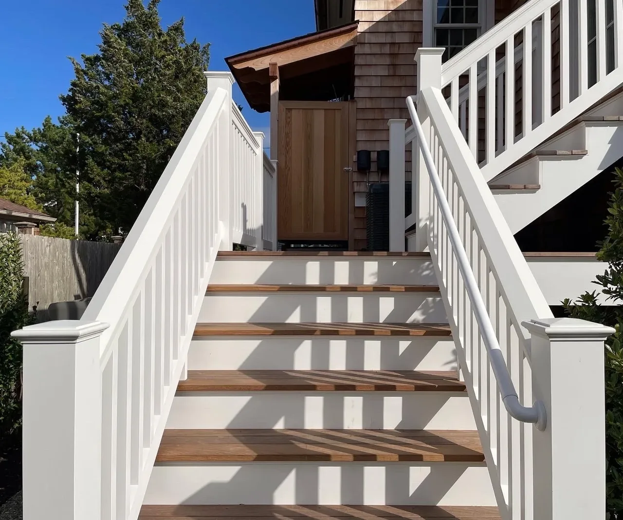 Outdoor staircase with white painted railings and wooden treads at the Hagerstrom residence entry door.