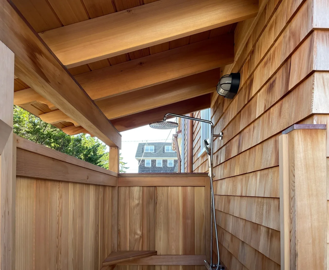 Covered outdoor shower with wood shingles and siding at the Hagerstrom residence by Richard Bubnowski Design.