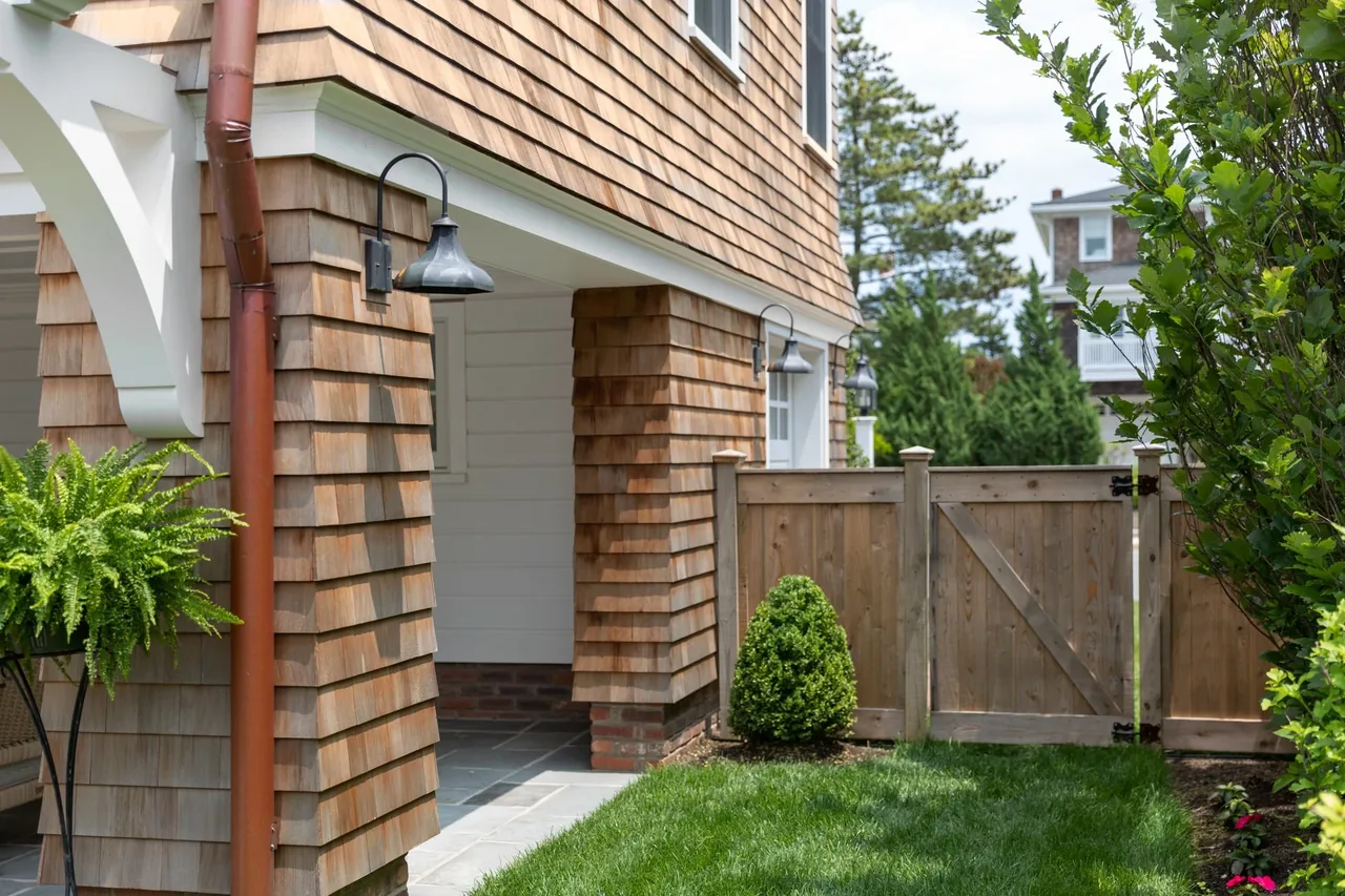 The Hagerstrom residence features wood shingle siding and a wooden privacy fence enclosing the garden space.