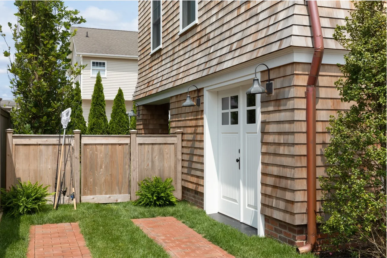 The Hagerstrom residence features wood shingle siding and white double entry doors under lantern-style wall lights.