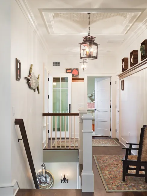 Hallway landing in a home featuring white walls, dark wood trim and railing, and a hanging lantern pendant light by Richard Bubnowski Design.