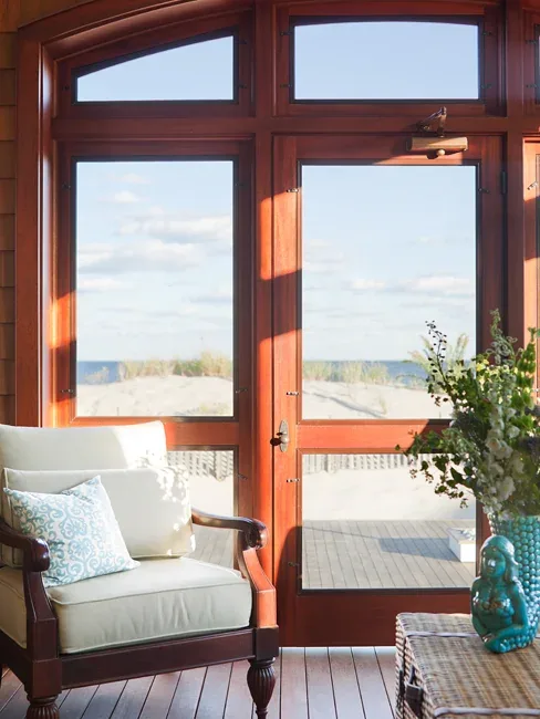 Interior seating area with traditional armchair and large glass doors framing a coastal view at South Surf Road, Silver Beach.