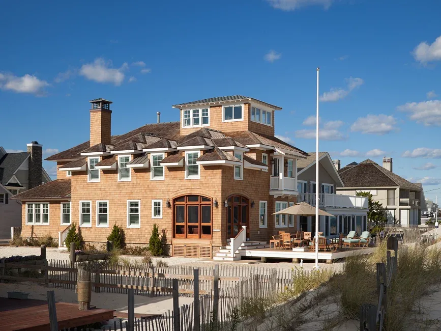 The South Surf Road beach house features wood shingle siding, dormer windows, and a spacious outdoor deck with seating and table umbrella.