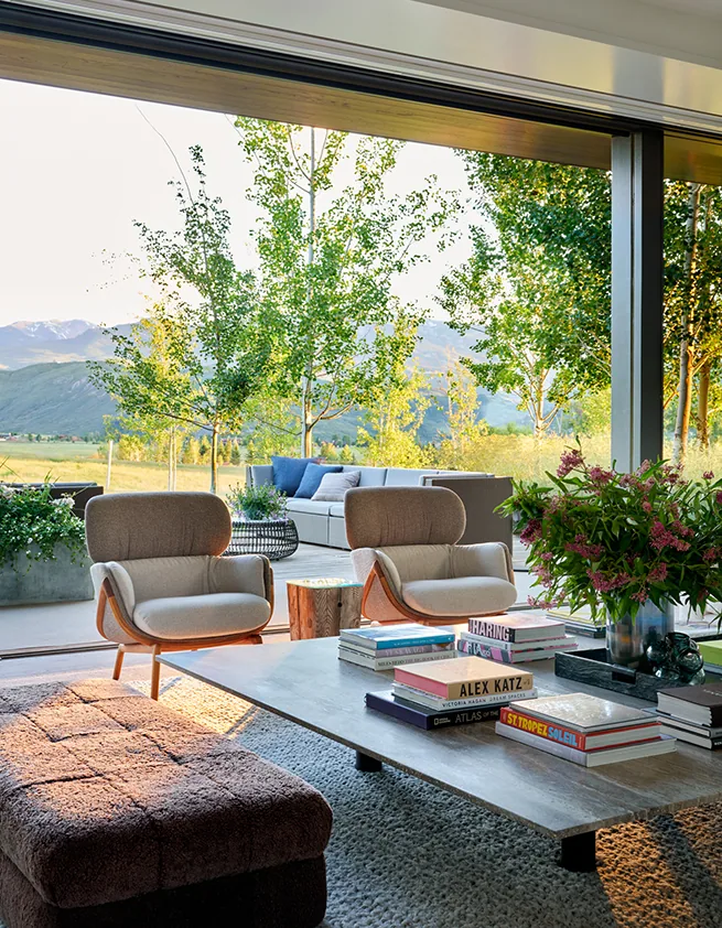 Open living area with upholstered seating and coffee table looking out over a landscape of trees and mountains.