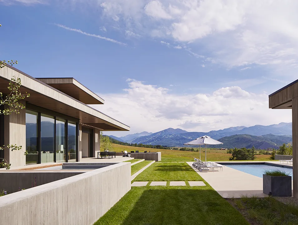 Mountain Modern project features flat roofs, concrete walls, floor-to-ceiling glass doors, and an outdoor pool with mountain views.