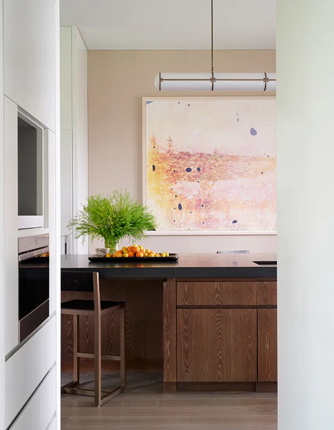 Modern kitchen featuring a dark wood island with black countertop and a hanging light fixture.