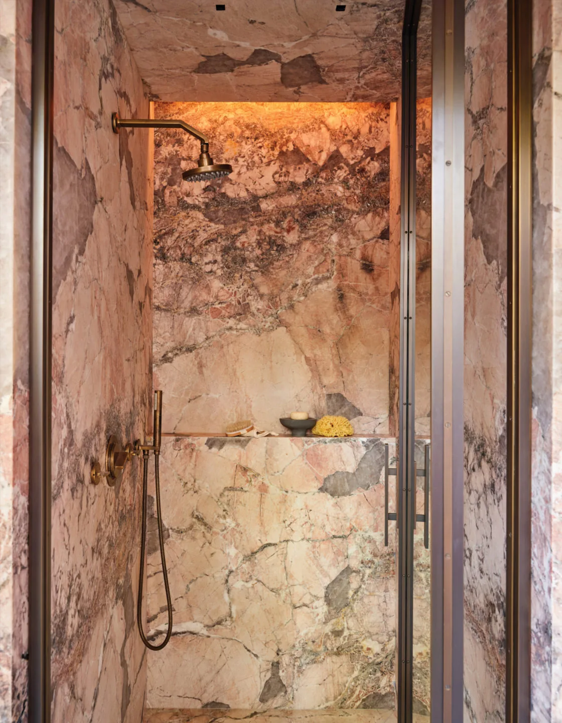 Bathroom shower features floor-to-ceiling marble tile with bronze fixtures and glass door.