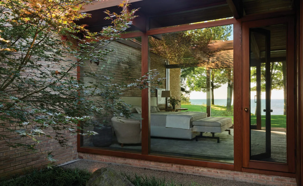 Bedroom inside the Lakeside Midcentury house with floor-to-ceiling windows offering lake views.
