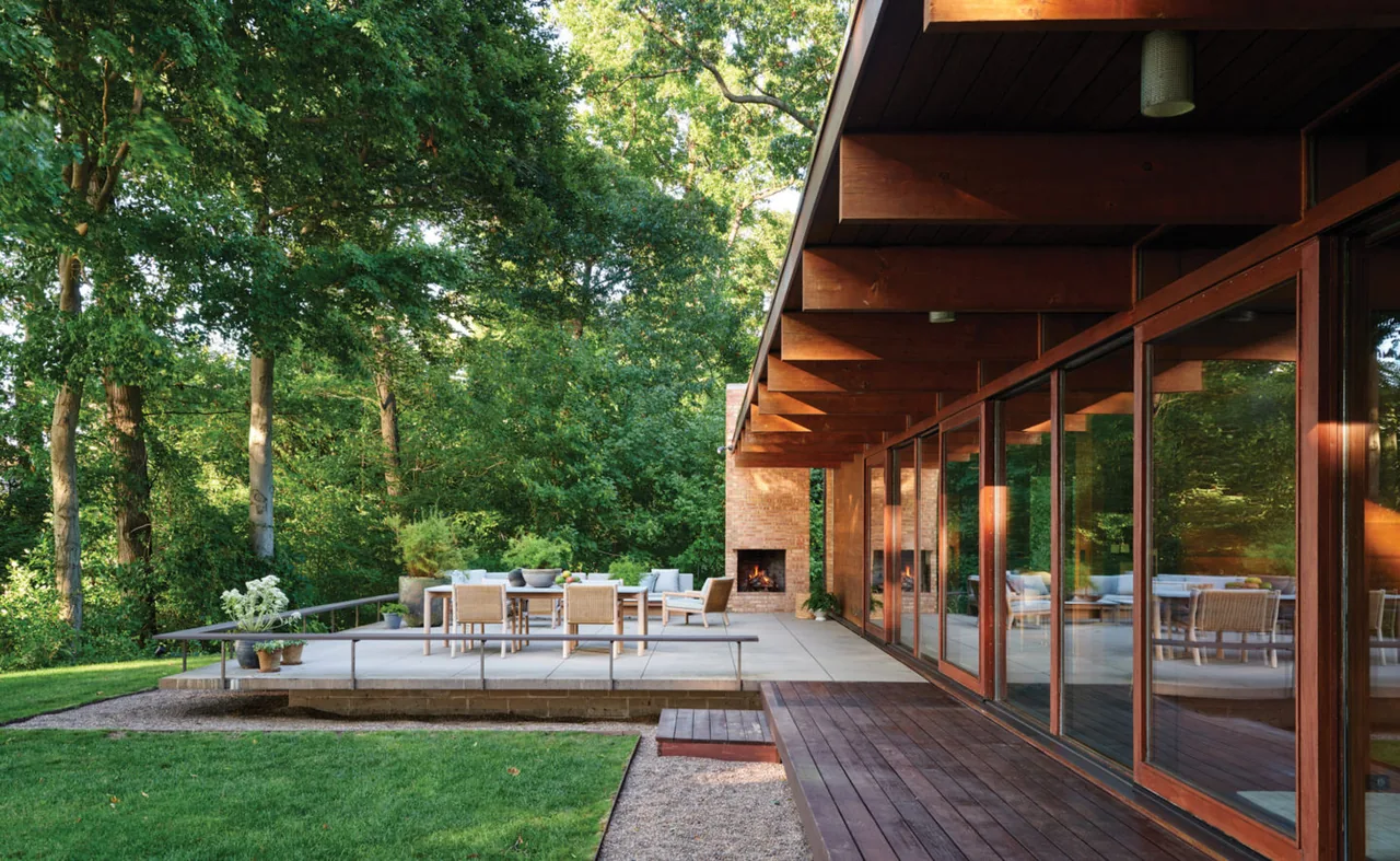 The Lakeside Midcentury project features a wood-paneled exterior with a glass wall, concrete patio, and outdoor fireplace.