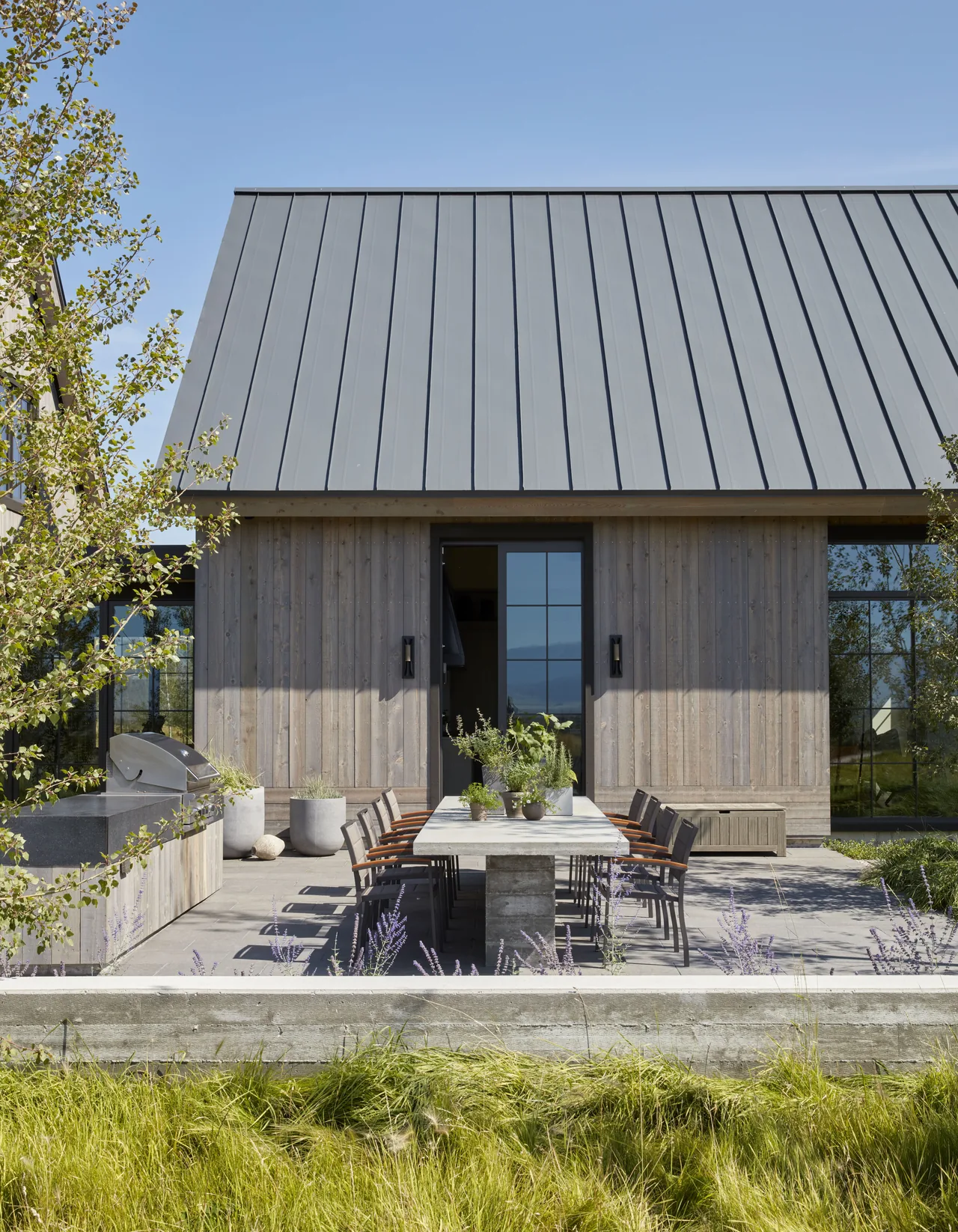 The Western Retreat features an outdoor dining patio with a concrete table and wood siding under a standing seam metal roof.
