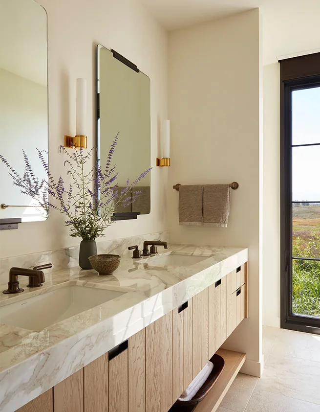 Western Retreat bathroom features a marble double vanity with wooden cabinetry and a large grid window providing a view outside.
