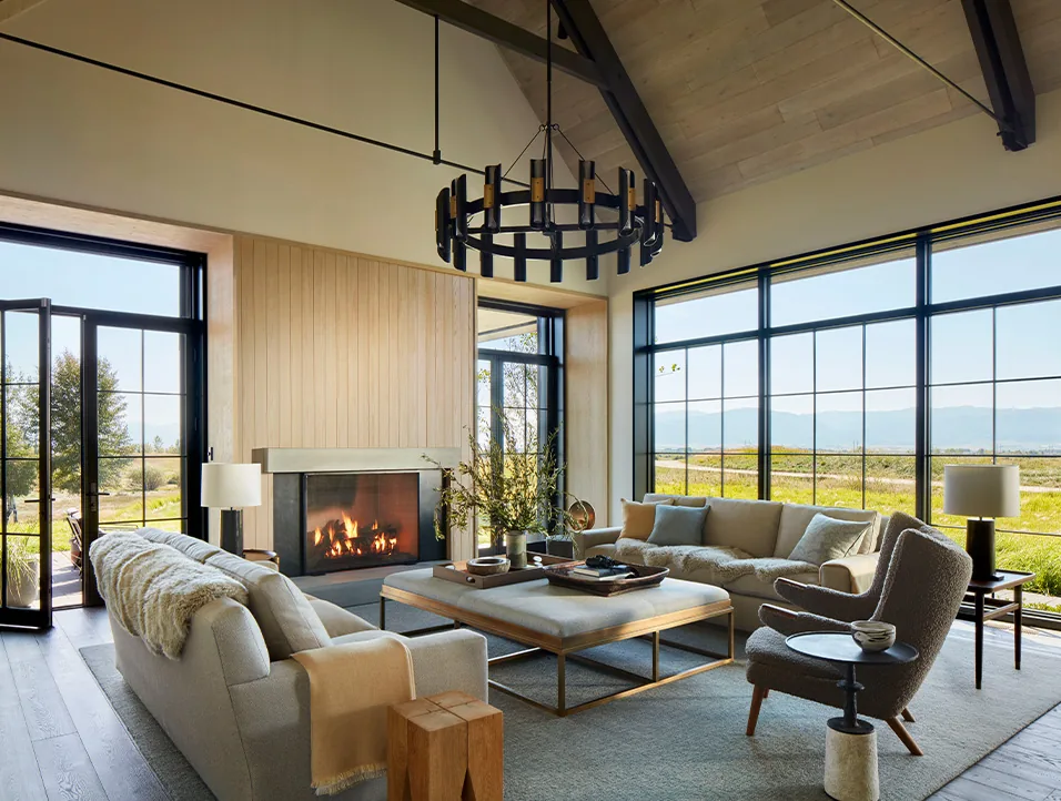 Living room features modern beige sofas, a fireplace, and floor-to-ceiling grid windows framing outdoor views at Western Retreat.