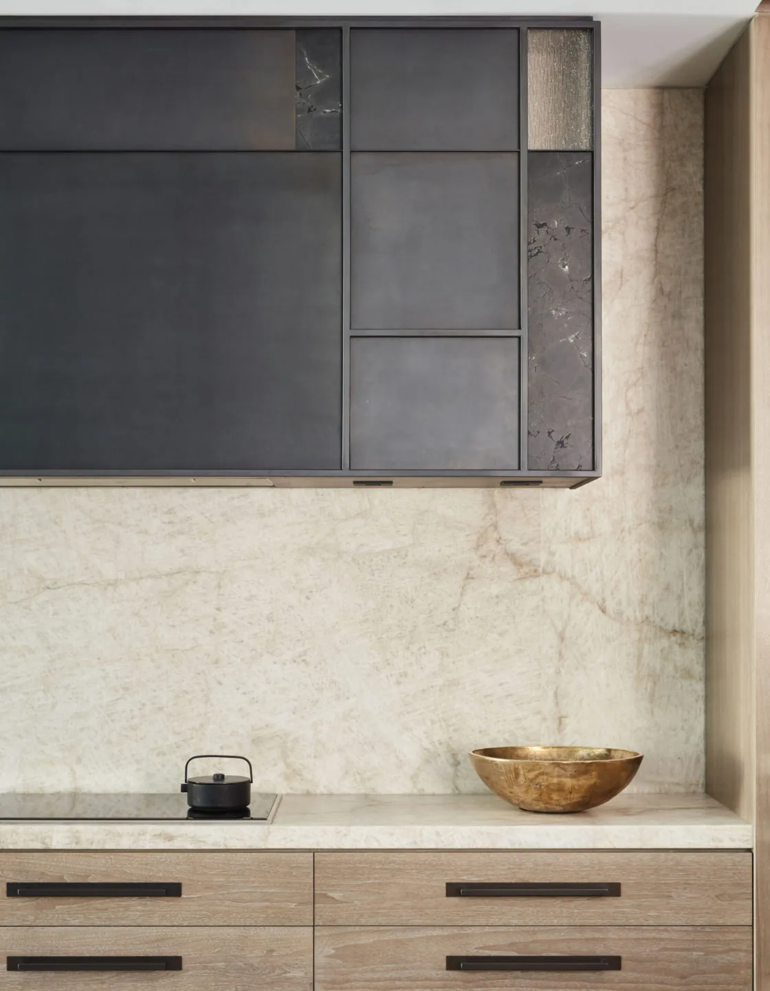 Modern kitchen with light wood cabinetry, marble countertop and backsplash, and dark square upper cabinets.