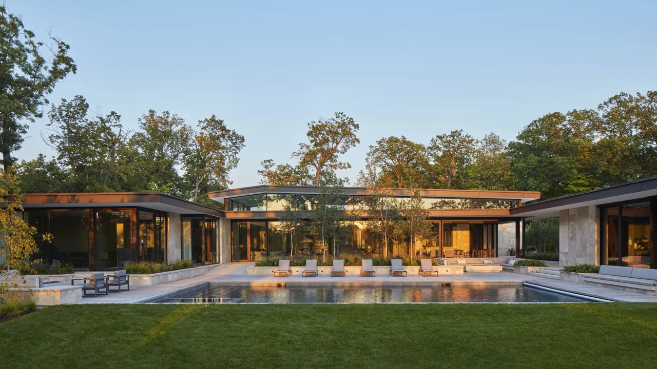 Midwest Sanctuary features a modern flat-roof home with floor-to-ceiling glazing opening to a pool and landscaped outdoor living area.