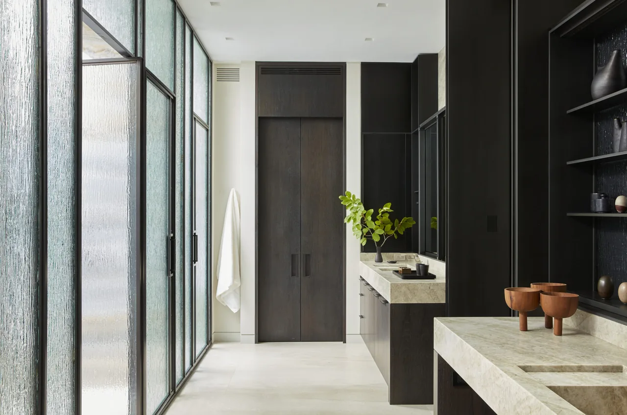 Bathroom features textured glass panels, dark wood cabinets, and stone countertops in the Midwest Sanctuary project.
