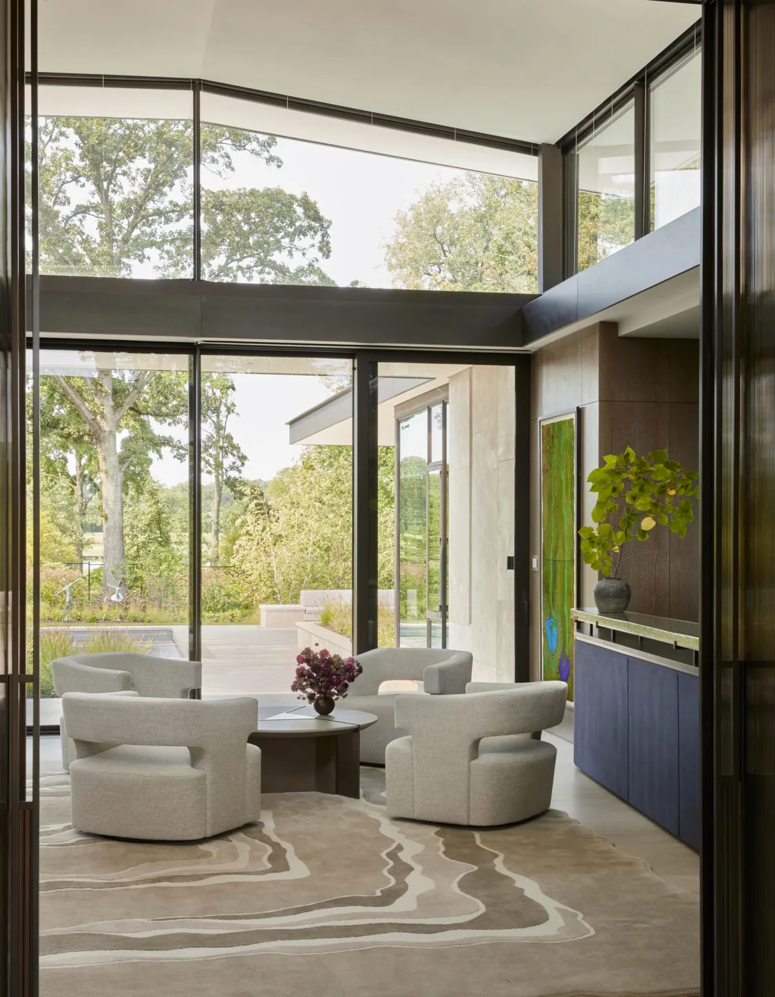 Seating area with curved armchairs and large glass windows overlooking a landscaped garden at Midwest Sanctuary.