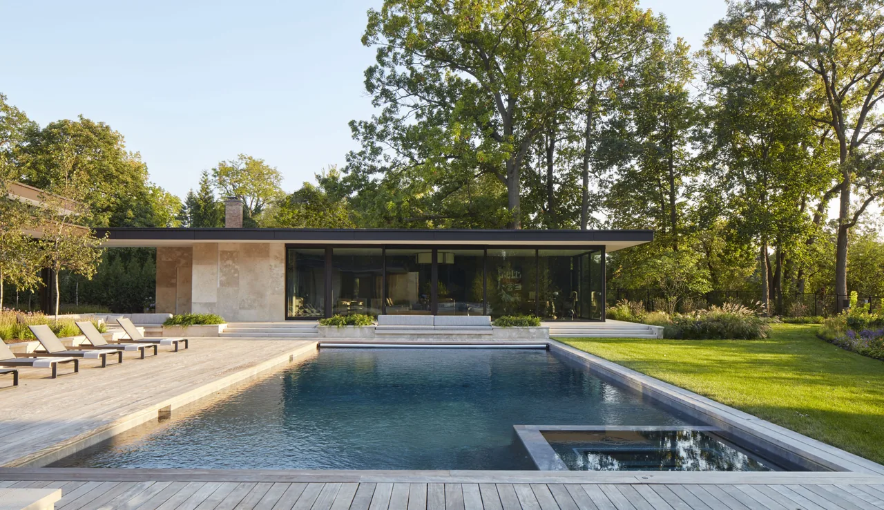 Mid-century modern inspired home with floor-to-ceiling glass walls and poolside lounging area