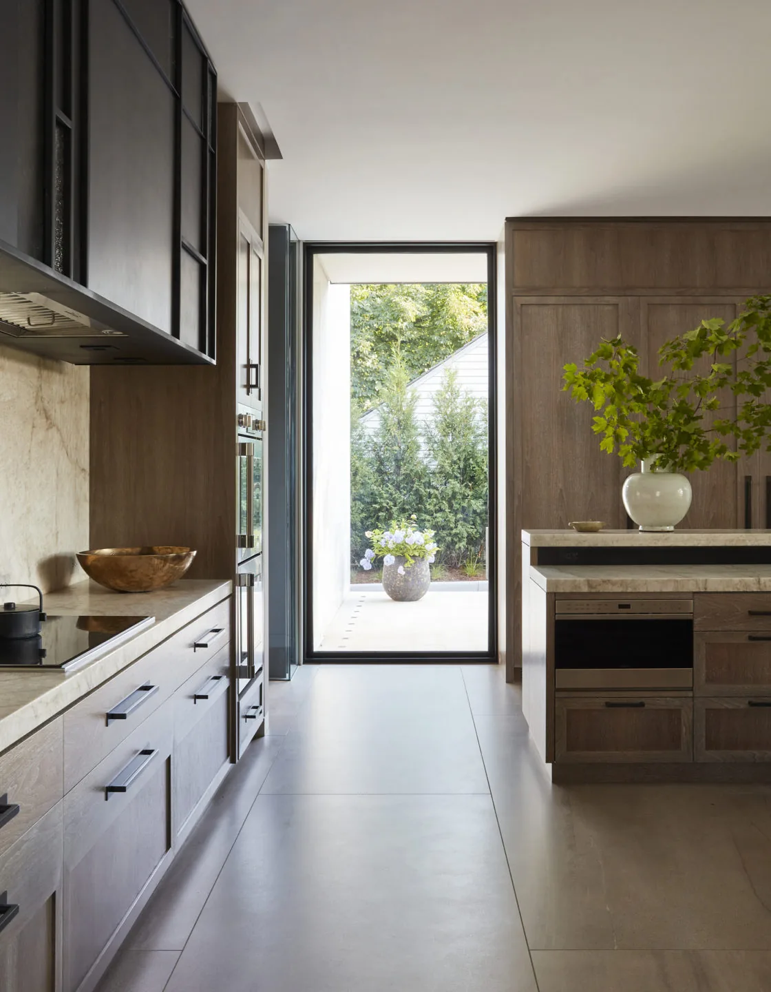 Kitchen in Midwest Sanctuary with wood cabinets, stone countertops, and a floor-to-ceiling glass door to the patio.