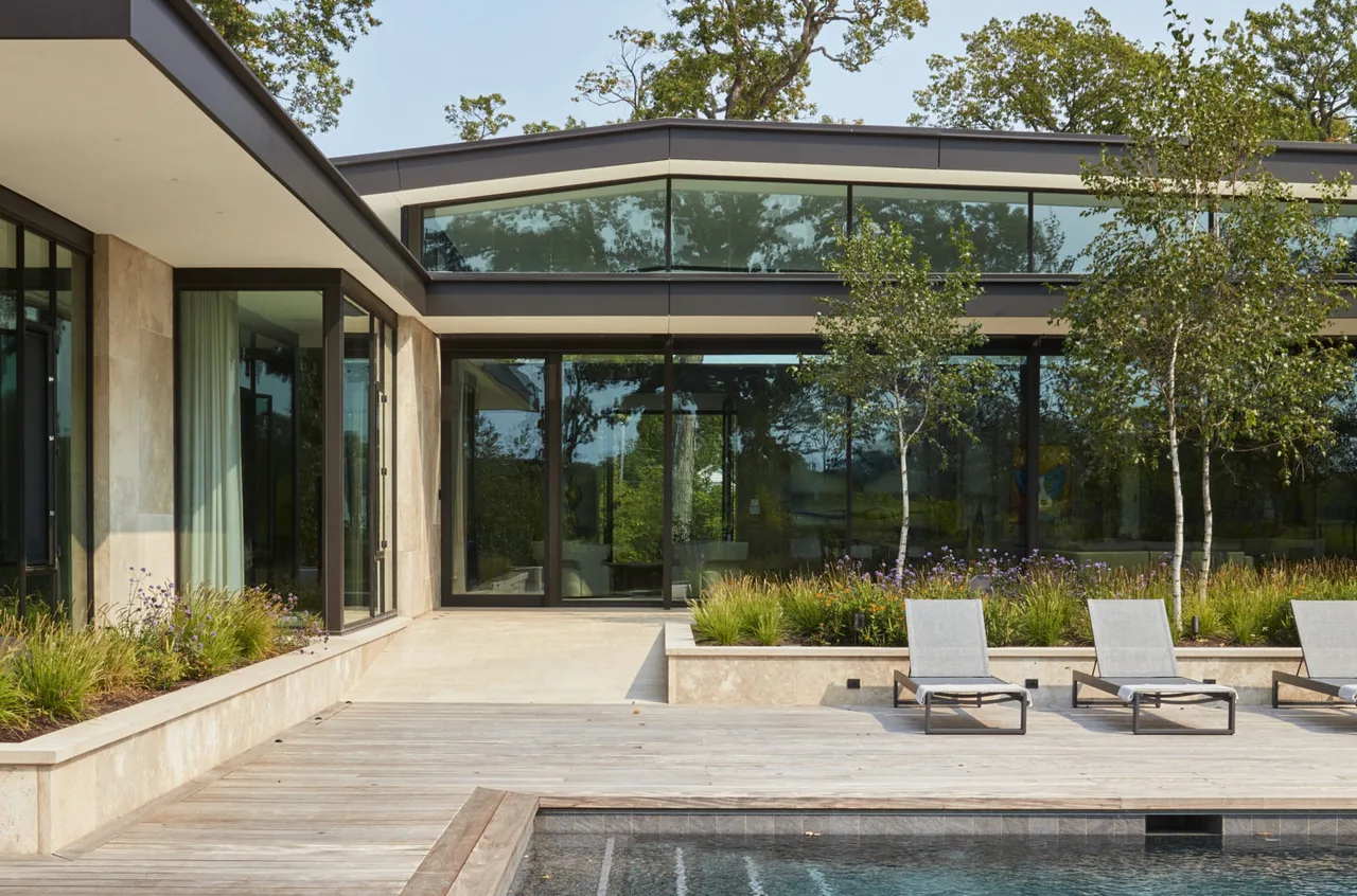 Exterior view of Midwest Sanctuary showcasing floor-to-ceiling glazing, a flat roof, and a landscaped garden by the pool.