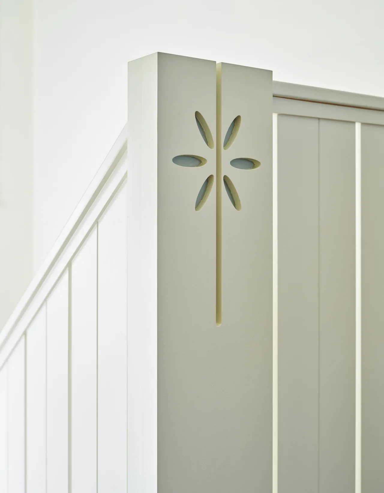 White wooden railing with a stylized flower cutout detail in the corner post.