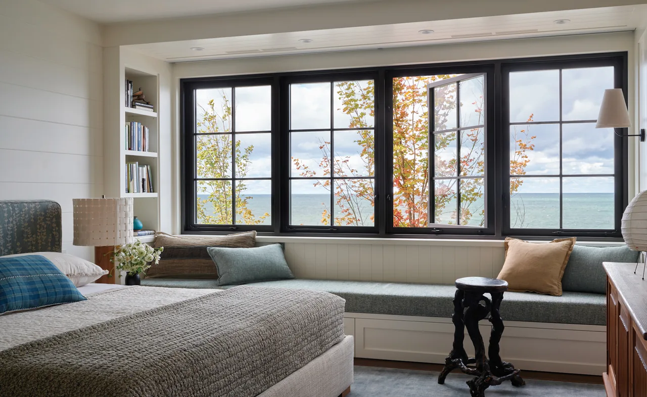 Bedroom featuring horizontal shiplap walls, built-in window bench, and multi-lite black window frames with lake view.