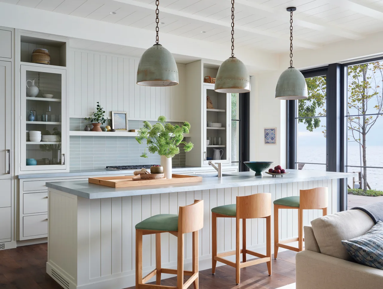 Kitchen with a white island and pendant lighting adjacent to sliding glass doors opening to a lake view.