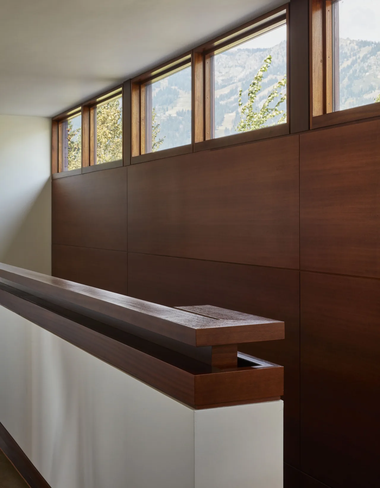Hallway features wood paneling and a row of small high windows revealing mountainous scenery.