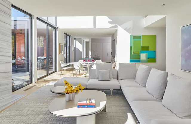 Modern living room with double-height ceiling and sliding glass doors leading to an outdoor patio.